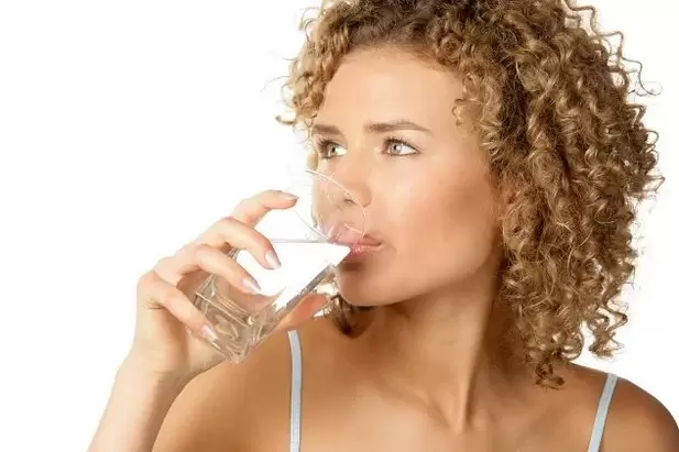 La ragazza segue una dieta per pigri, bevendo un bicchiere d'acqua prima di mangiare